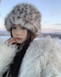 Detail of leopard print faux fur bucket hat styled with a white plush winter coat