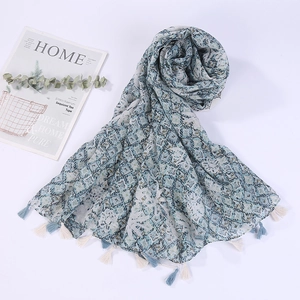 Detail of printed geometric scarf with soft blue diamond patterns and bicolor tassels