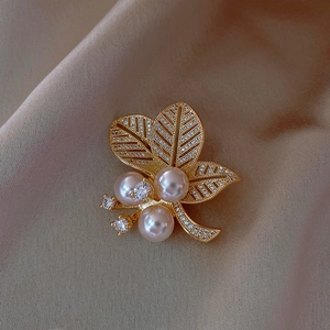 Elegant gold leaf brooch featuring white pearls and shimmering zircons on satin
