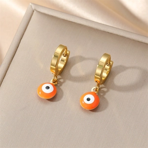 Detail of golden evil eye hoop earrings with orange enamel on a silk background