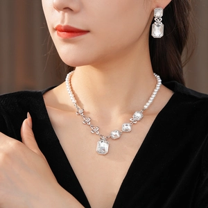 Detailed view of silver necklace and earrings set featuring square crystals and white pearls