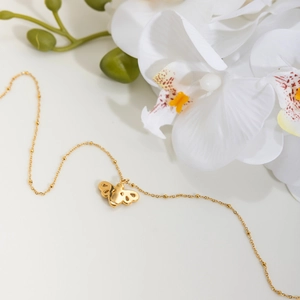 Detailaufnahme der goldenen Bienen-Halskette mit Perlenkette und Blumen-Deko