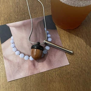 Minimalist wooden acorn pendant necklace with a sleek silver metal tube and snake chain