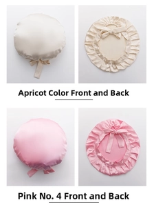 Detail view of pink and beige silk sleep caps with ruffled edges and adjustable bow ties
