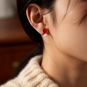 Gros plan de boucles d'oreilles perles papillon rouge portées par un mannequin