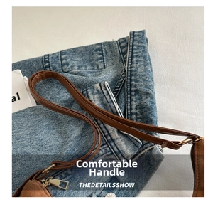 Detail of brown suede tote with leather strap and golden buckle on denim background