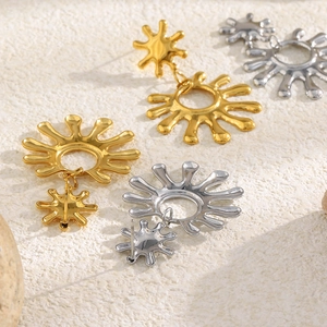 Vue détaillée de boucles d'oreilles soleil en finitions métalliques or et argent poli