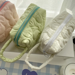 Close-up of quilted floral cosmetic bags in pink, green, and white with carry handles