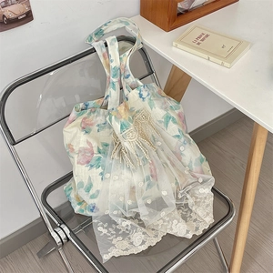 Close-up of floral linen shoulder bag with white lace embroidery and mesh detailing
