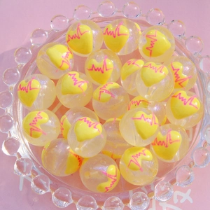 Vue détaillée des perles transparentes de 16mm avec cœur jaune et motifs de ligne de pouls