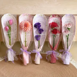 Five assorted faux flowers in artistic patterned sleeves with purple ribbon bows