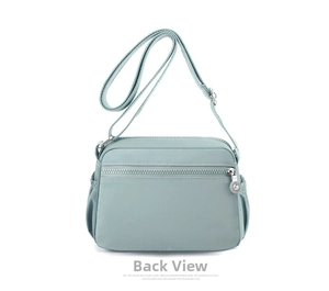 Detail view of the water-resistant nylon shoulder bag's back zipper pocket and adjustable strap