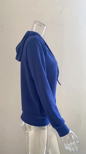 Dettaglio del maglione blu con cappuccio che mostra la trama a coste e i polsini elastici