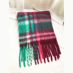 Detailed view of woven green and wine red plaid scarf featuring soft fringe tassels