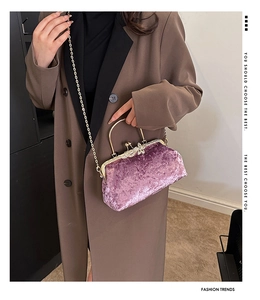 Macro detail of purple velvet handbag featuring sparkling rhinestone bow clasp and gold chain
