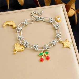 Detailed shot of gold cherry and heart charms on silver chunky link bracelet