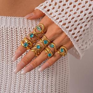 Détail de bagues en or avec pierres bleues et zircons portées sur la main d'un mannequin