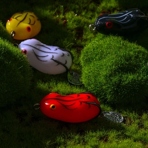 Macro shot of four colorful soft frog fishing lures with spinning blades on moss