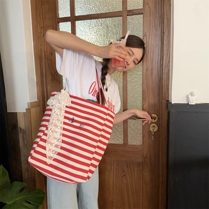 Detail of red and white striped canvas tote bag with lace bow and embroidery