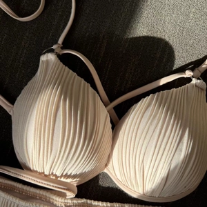 Detail view of beige textured bikini top with vertical pleats and thin drawstrings