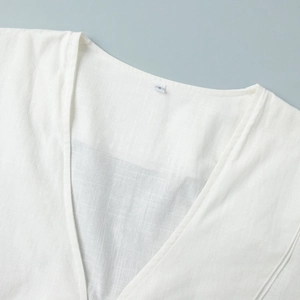 Detail of white cotton shirt V-neck stitching with size S label on textured fabric