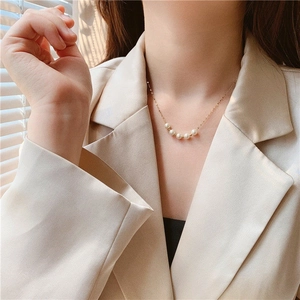 Close-up of minimalist gold lip chain necklace with 5 white pearls on a model