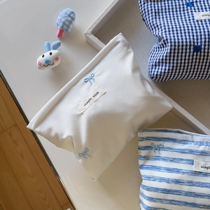 Blue and white striped checkerboard cosmetic bag with embroidered bow and brand tag