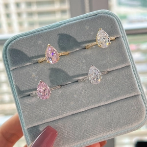 Macro view of pear cut sparkling stones on gold and silver pavé bands in a box