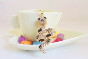 Detailed close-up of a golden snake pendant set with clear and black rhinestones