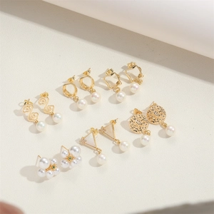 Detailed set of six gold-tone geometric earrings with white pearls on a textured background