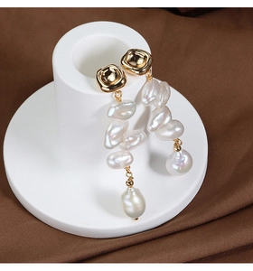 Detailed close-up of French baroque earrings with natural pearls on a gold plated stand