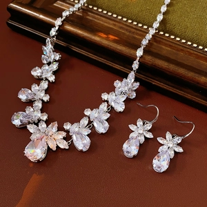 Detailed close-up of floral zircon necklace and teardrop earrings set on vintage wood