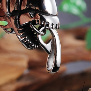 Macro shot of silver metal alien skull pendant with sharp teeth on vintage sweater chain