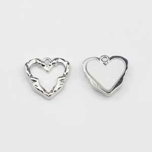 Detailed view of silver heart charms featuring textured finish and white enamel inlay