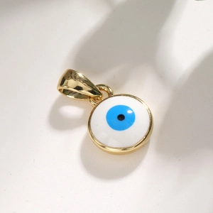 Macro view of a round gold-plated Evil Eye charm with blue and black enamel inlay