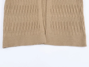 Macro detail of warm khaki knit fabric showing ribbed hem and tight textured weaving pattern