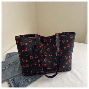 Detailed close-up of a large black nylon tote bag featuring vibrant cherry prints and straps