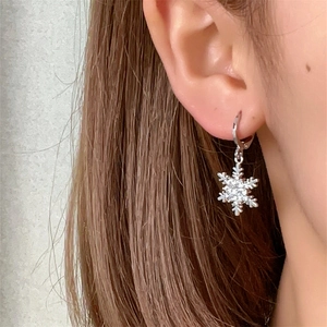 Macro detail of silver snowflake drop earring with shimmering zircon stones on a model