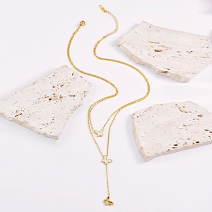 Elegant gold butterfly pendant necklace set on white background with decorative stones