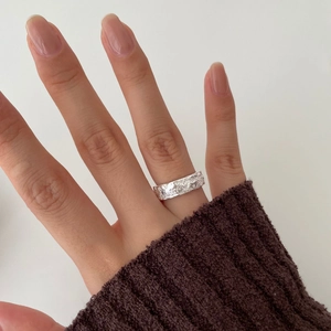 Detail of an irregular hammered texture 925 silver ring worn on a model's hand