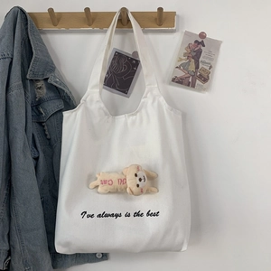 Close-up of white canvas tote with cute khaki cat plush doll and handwritten lettering
