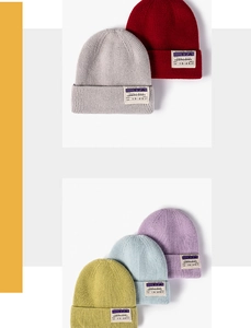 Detail of ribbed knit beanies in various colors with vintage boarding pass woven labels