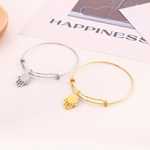 Dettaglio di bracciali regolabili a Mano di Fatima in acciaio oro e argento su carta