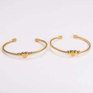 Golden stainless steel heart twisted cable open cuff bracelet on white background