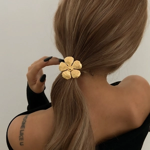 Elegant gold metal five-petal flower hair accessory worn on a stylish ponytail