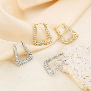 Close-up of geometric U-shaped earrings in gold and silver finish with sparkling rhinestones