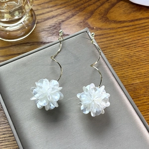 Macro detail of elegant golden spiral tassel earrings with white shell flower petals