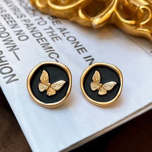 Close-up of vintage butterfly earrings with gold relief on a black round base