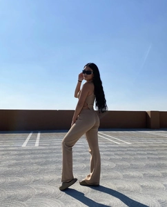 Outdoor low angle shot of tan knitted cut-out halter top and high-waisted flared trousers