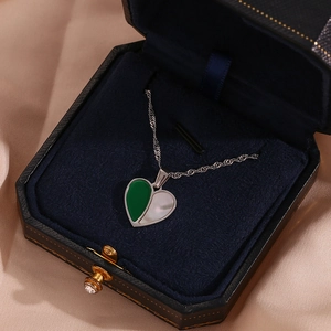 Close-up of heart pendant with green and pearl shell mosaic in a luxury jewelry box